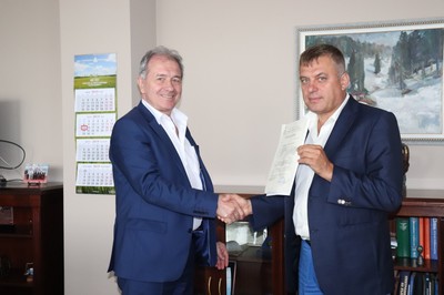 Двама души се здрависват и позират с документ