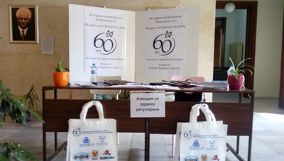 Закрит дисплей с брошури, растения и торби по повод 60-годишнината на Агенцията за ядрено регулиране на България.