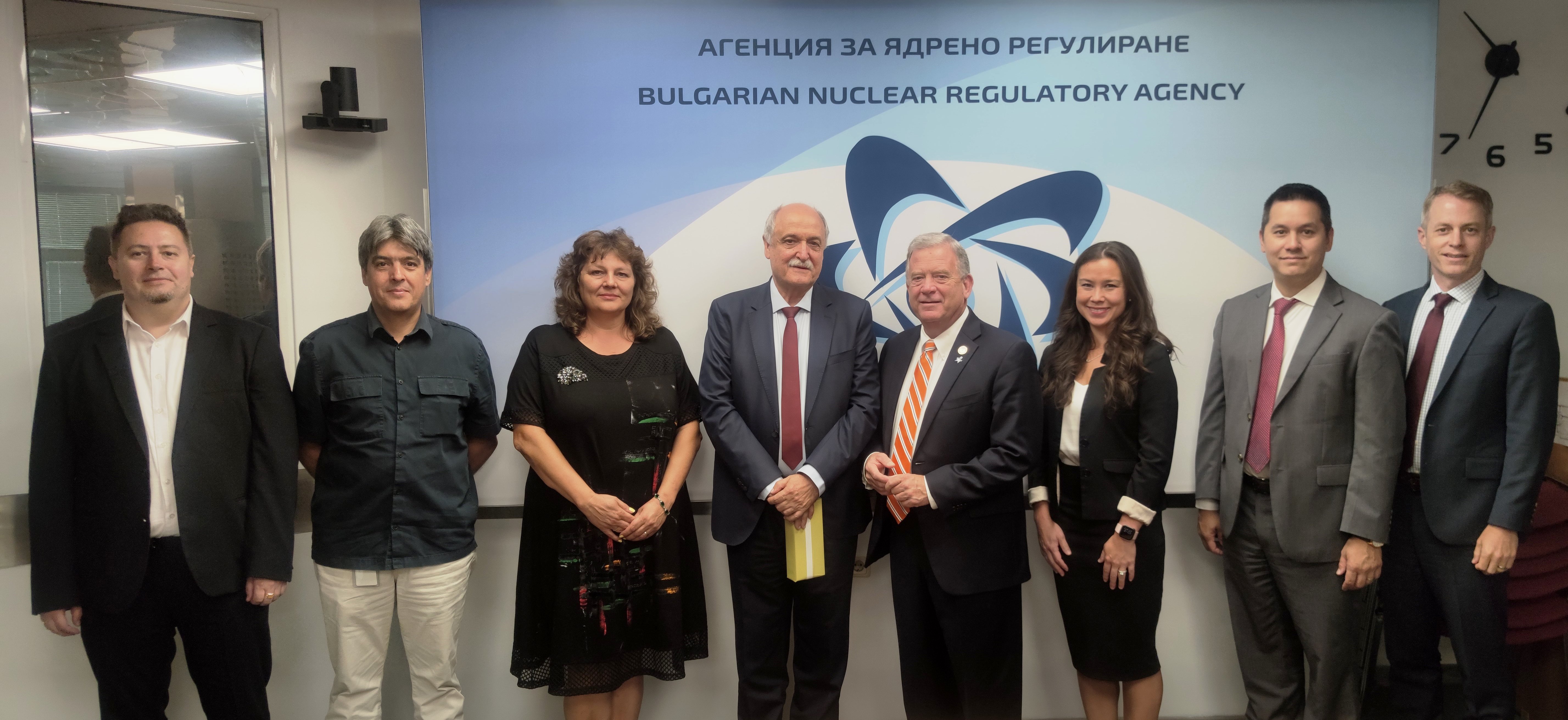 Група от осем лица пред таблица на Агенцията за ядрено регулиране на България.