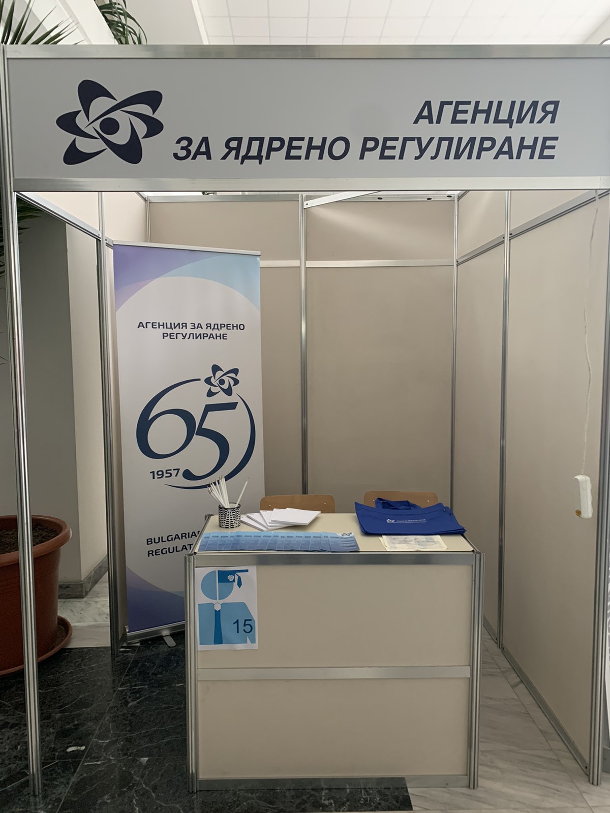 Агенция за ядрено регулиране. Щанд с информационни материали: синя папка, брошура. Банер за 65 години дейност.